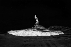 Wave rushing through a rock tunnel which surfers use to access the water behind the waves.